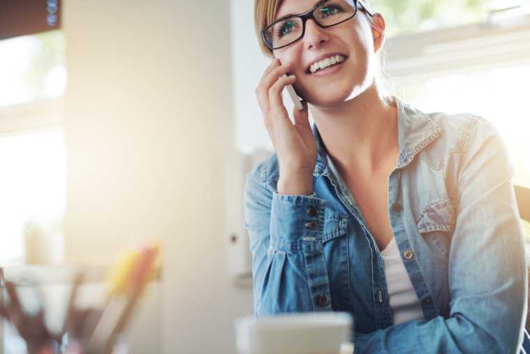 Young woman wearing glasses smiling while on the phone