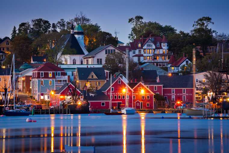 brightly painted seaside buildings are lit up at dusk in lunenberg
