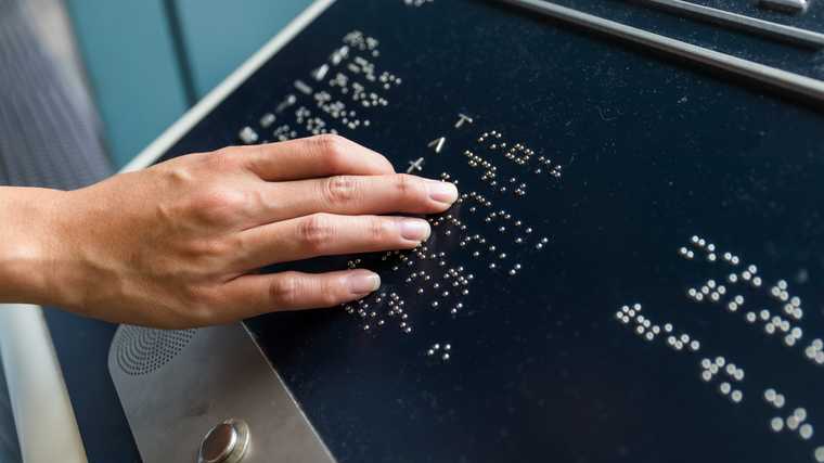 Hand reading braille kiosk signage