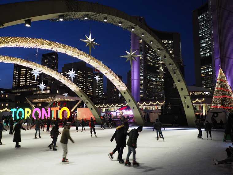 crowd skating at toronto city hall with lights and holiday decorations lit up