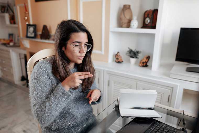 Young woman signing while on a video call at her laptop