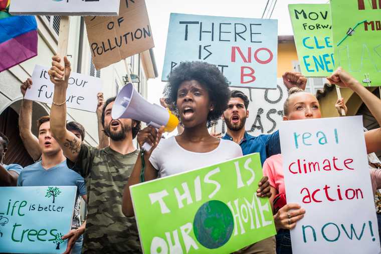 group of people chanting and holding home made signs advocating for climate action and a clean planet