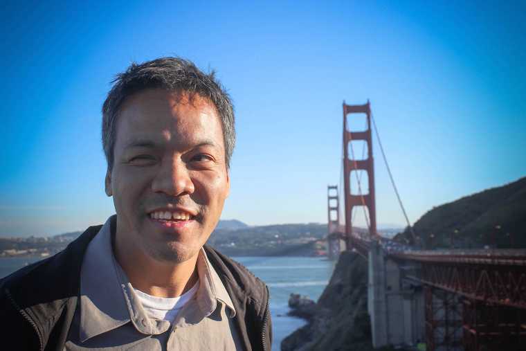 Jennison Asuncion smiling and posed in front of the golden gate bridge
